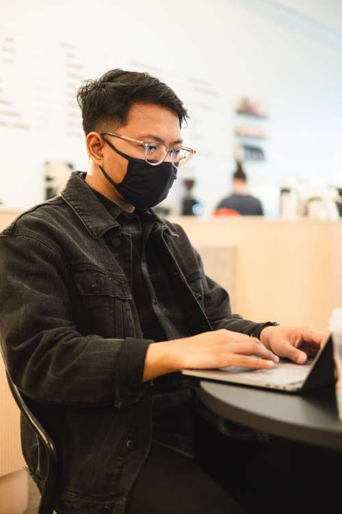 Man Works On His Laptop And Wears Facemask Photo