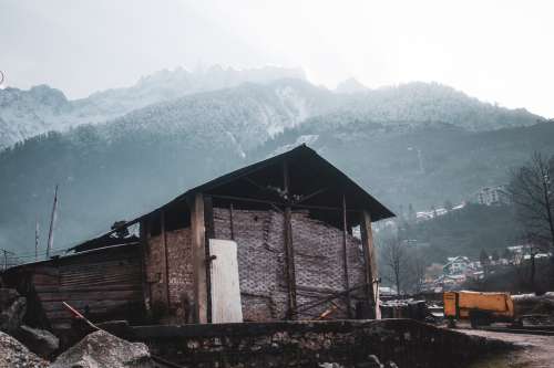 Rustic Building With Snow Capped Mountains Behind It Photo