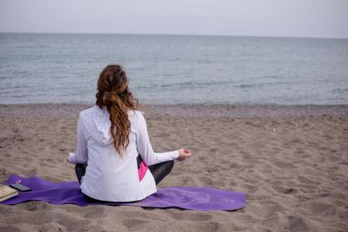 Person Cross Legged On A Yoga Mat At The Beach Photo