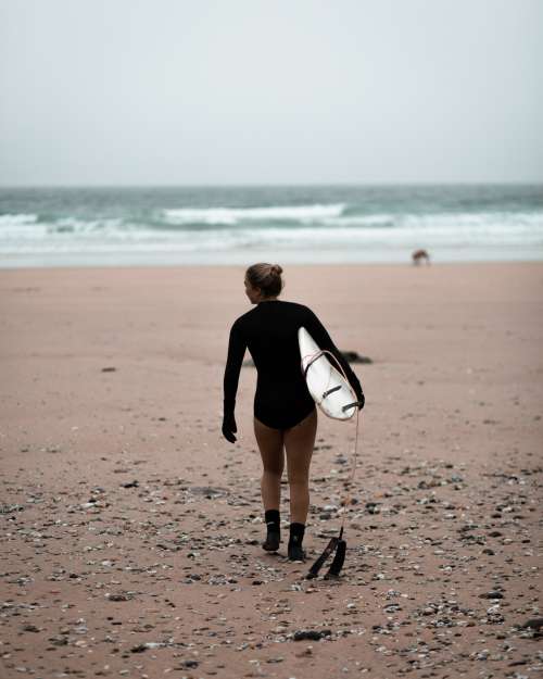 Person Carries Surfboard On The Beach Photo