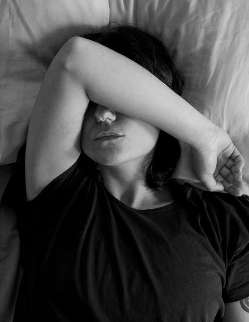 Person Lying With Their Arm Up In Bed In Black And White Photo