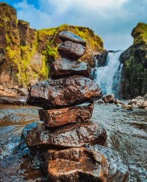 Stack Of Wet Rocks With A Waterfall Behind Photo