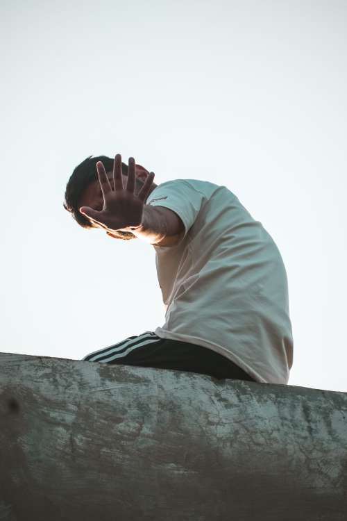 Person On A Ledge Hand Up To Hide Their Face Photo