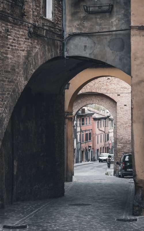 A Cobblestone Street Through An Archway Photo