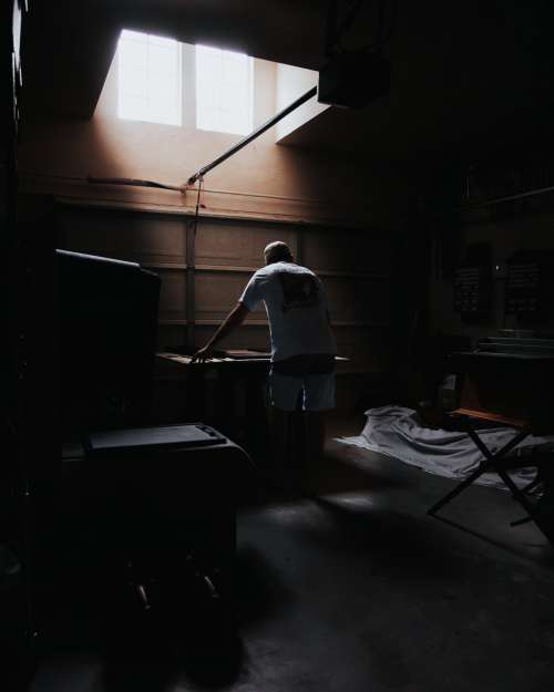 Light Pours In Illuminating A Person Leaning Over A Table Photo