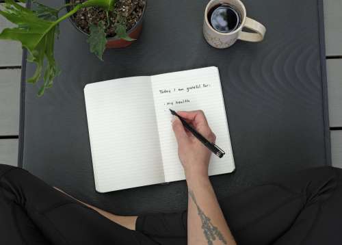 Person Writing Out What They Are Grateful For In A Notebook Photo