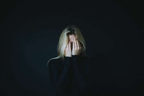 A Blond Woman Hold Her Hands Up To Hide Her Face Photo