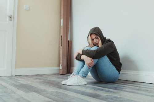 Woman Sits On The Floor And Holds Her Legs Photo