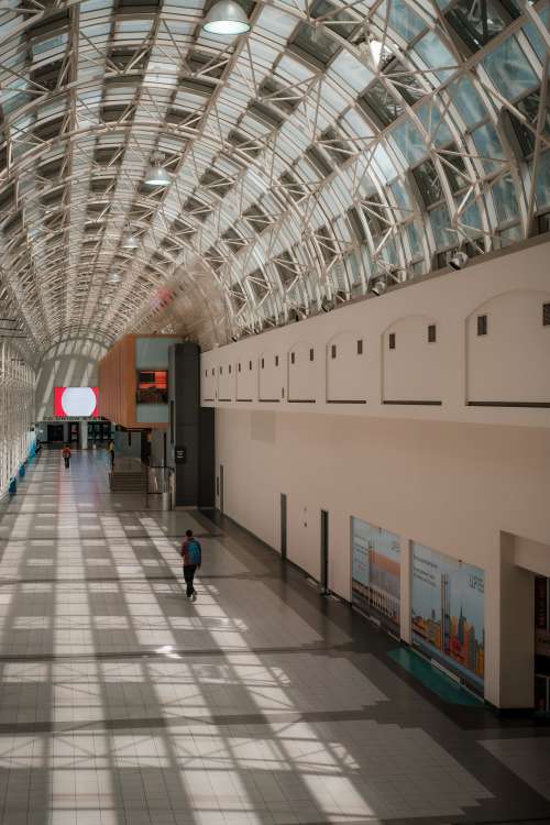 Person Walks Down A Wide Atrium With A Curved Ceiling Photo