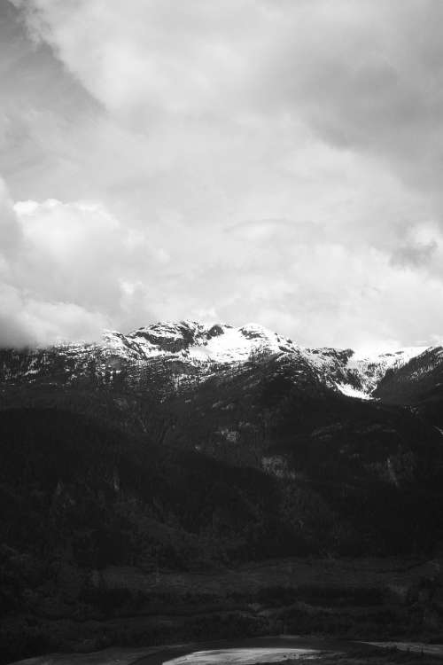 Mountain Tops Under A Cloudy Sky In Monochrome Photo