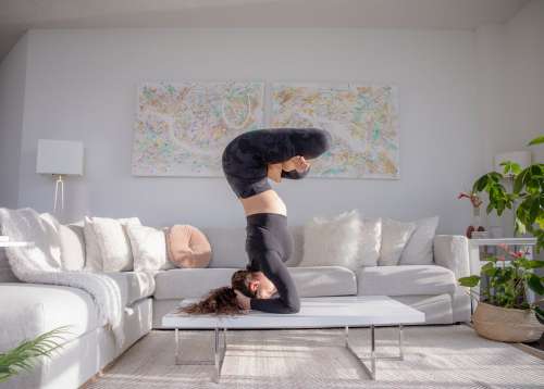 Woman Practices Advanced Yoga Pose On Coffee Table Photo