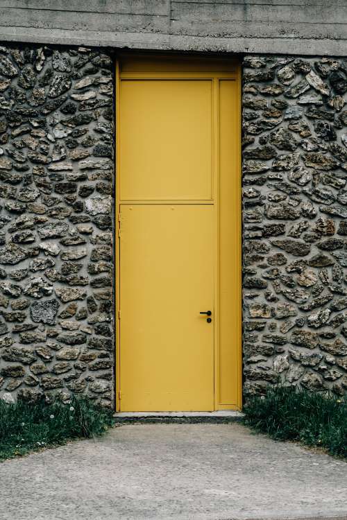 Stone Building With A Thin Bright Yellow Door Photo