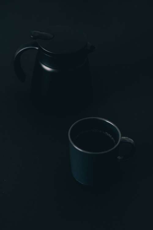 Coffee Mug And Pot Sitting On A Black Surface Photo
