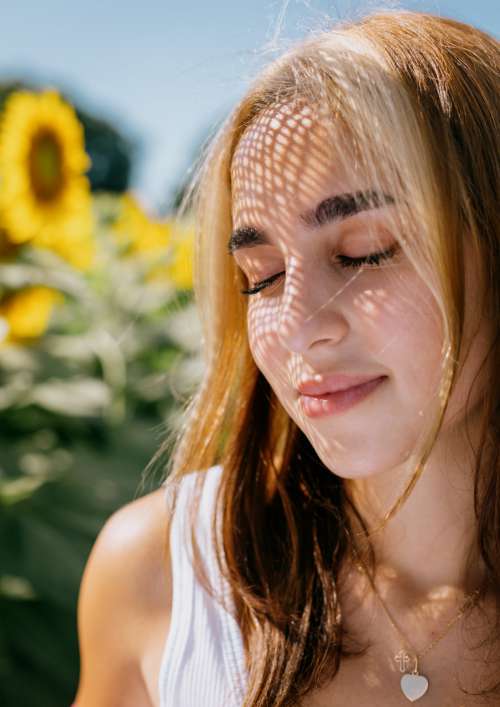 A Woman With Closed Eyes Surrounded By Sunflowers Photo