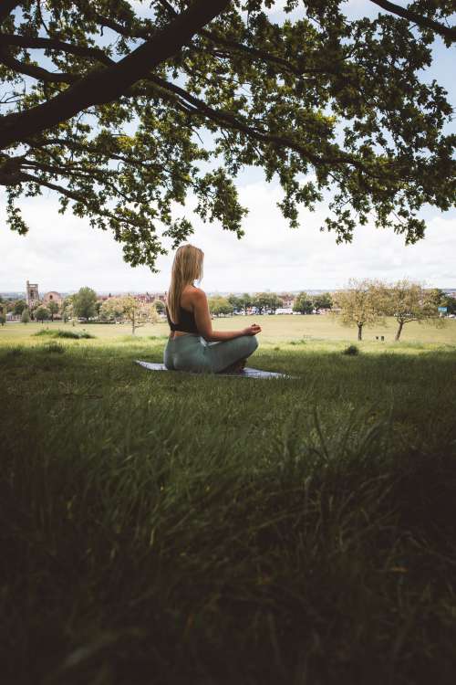 Woman Meditates Cross Legged Under A Tree Photo