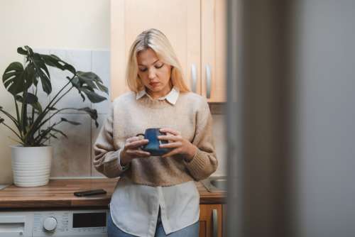 Woman In Her Kitchen Looks Into Her Mug Photo
