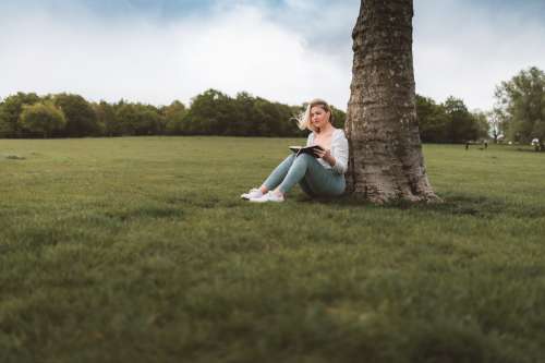 Woman Sits Under A Tree And Reads A Book In The Breeze Photo