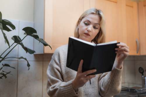 Woman Reads A Novel In Her Kitchen Photo