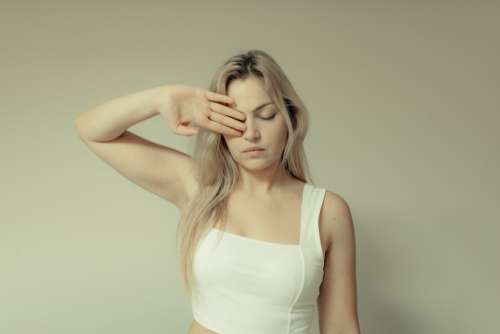 Woman Holds Her Arm Up And Covers Her Left Eye Photo