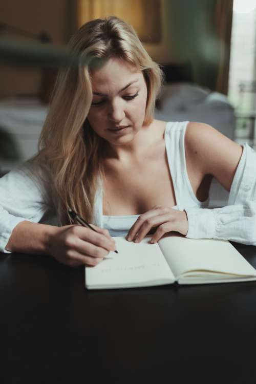 Woman Writes In A Open Notebook In Her Lounge Photo