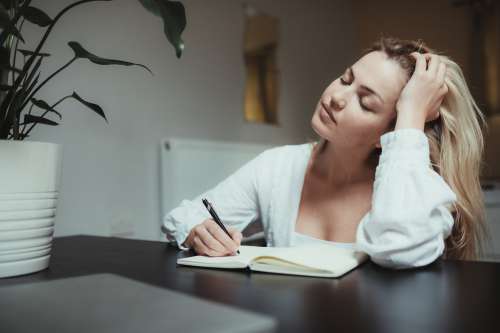 Woman Closes Her Eyes While Journalling In A Notebook Photo