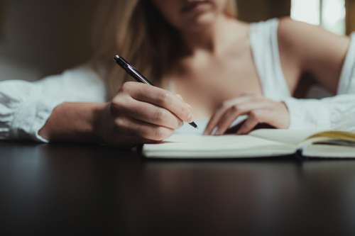 Hand Holding A Pen Over A Notebook Over Black Table Photo