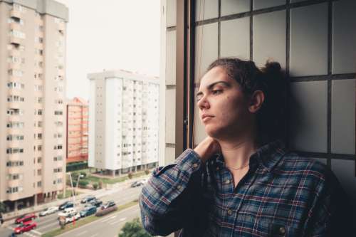 Woman Leans On A Tiled Wall And Looks Out The Window Photo