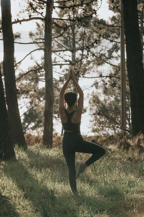 Person Does Yoga Pose Outdoors Surrounded By Trees Photo