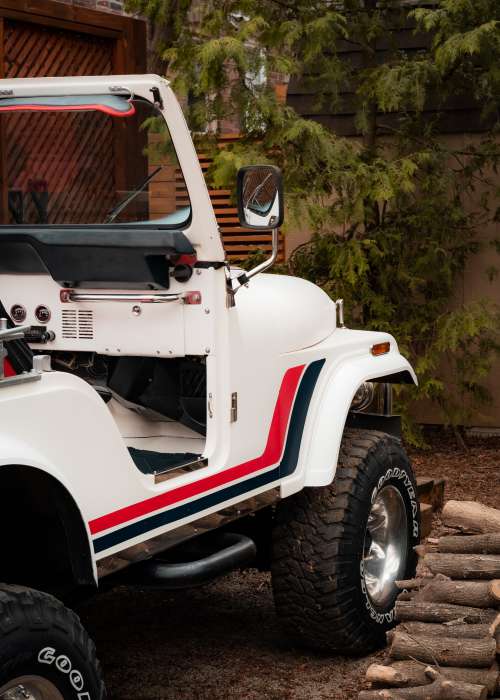 A White Convertible Jeep With A Red And Blue Stripe Photo