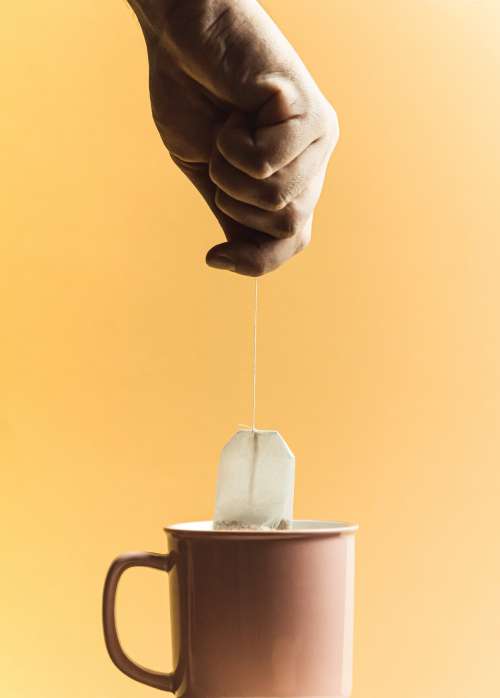 Hand Holds A Tea Bag Over A Cup Photo