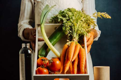 Person Tilts A Box Full Of Vegetables Towards The Camera Photo