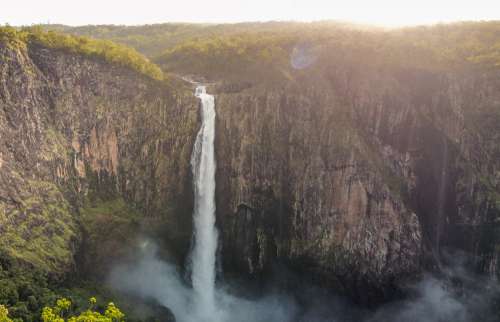 Waterfall Creating Mist Over A Large Cliff With Trees Photo