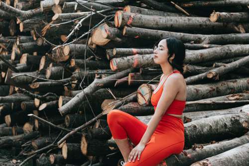 Woman Sits By Large Wooden Branches Photo