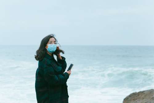 Woman In Face Masks Stands In Front Of Ocean View Photo