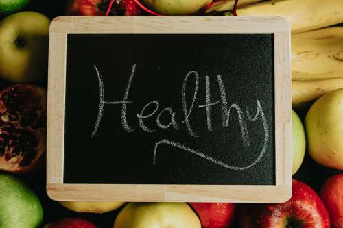 Chalkboard With The Words Healthy In Cursive Lays On Fruit Photo