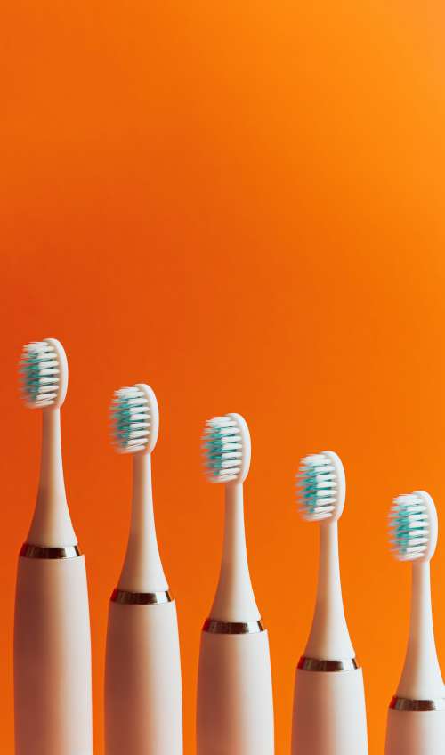 Toothbrushes Lined Up In A Row Against Orange Photo