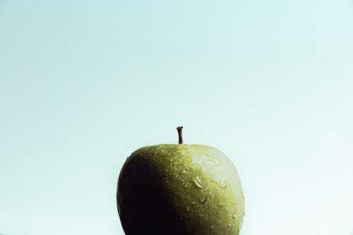 A Wet Crisp Green Apple Against A Light Blue Background Photo