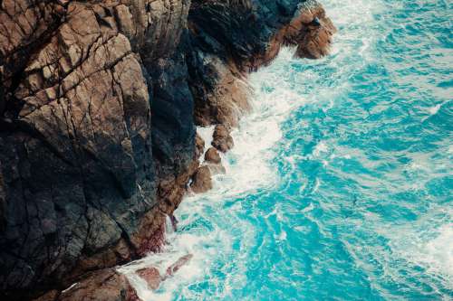 Aerial View Of Aqua Blue Waves And A Rocky Cliff Photo