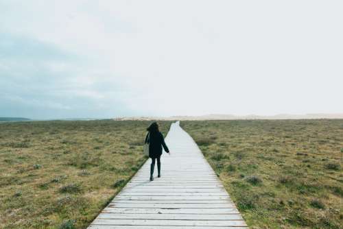 Woman Walks Down A Flat Wooden Boardwalk Photo