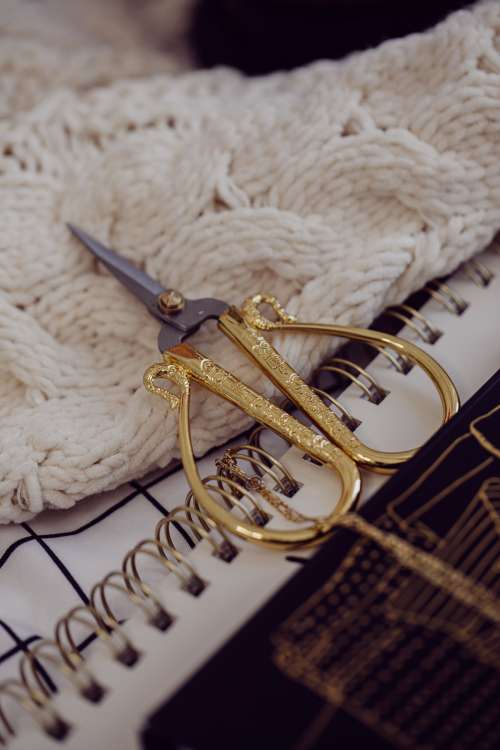 Carved Gold And Silver Scissors Lay On A White Fabric Photo