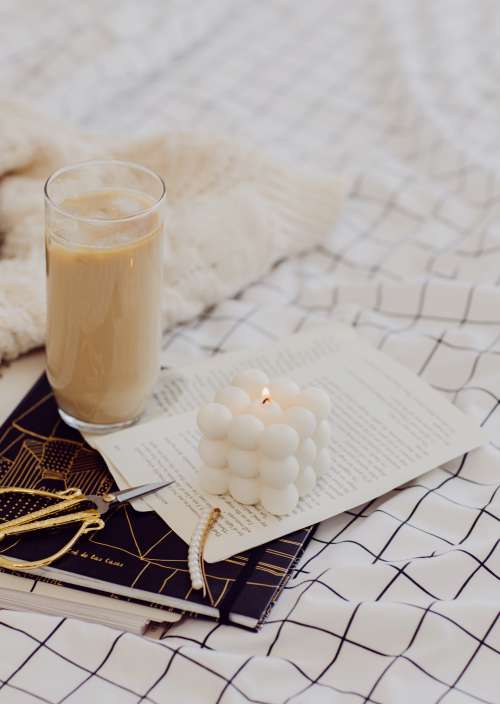 A Lit Candle With Iced Coffee And Hair Accessories Photo