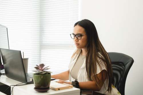 Woman Works At A Two Tier Desk And Concentrates Photo