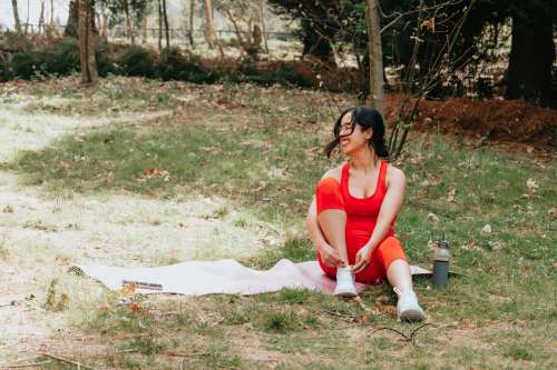 Woman Sits On A Pink Yoga Mat On Green Grass Photo