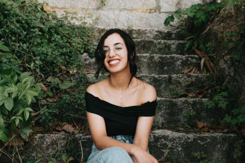Woman Sits On Stone Steps And Smiles Towards The Camera Photo