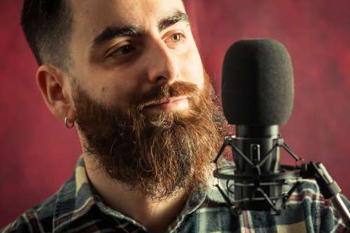 Bearded Man Standing Behind A Black Microphone Photo