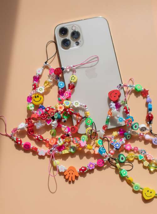 Flatlay Of A Cell Phone And Colourful Beaded String Photo