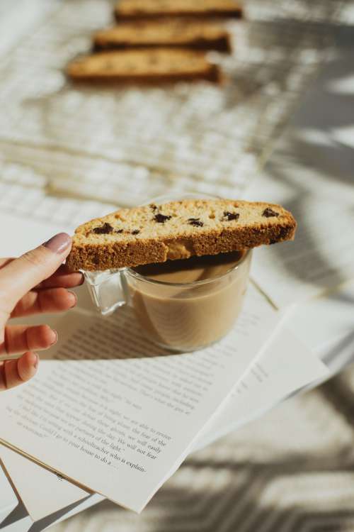 Hand Places Biscotti Cookie Over A Cup Of Coffee Photo