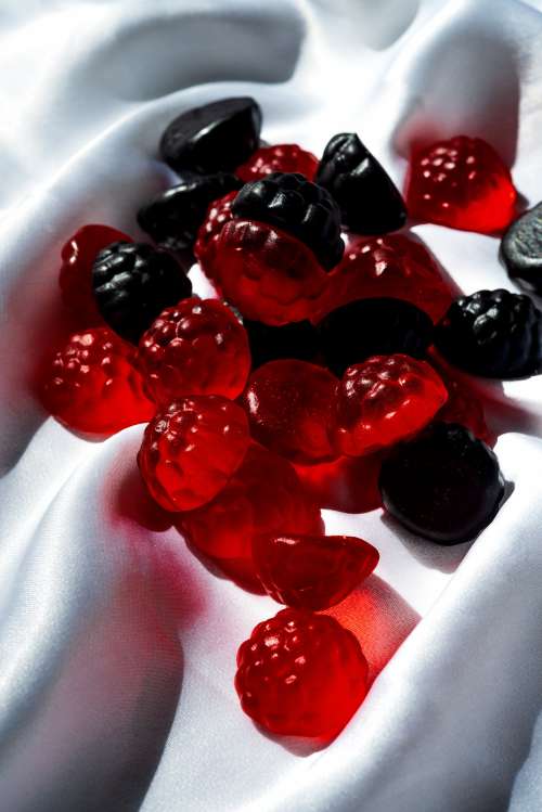 Red And Blue Candy In The Shape Of Berries On White Silk Photo