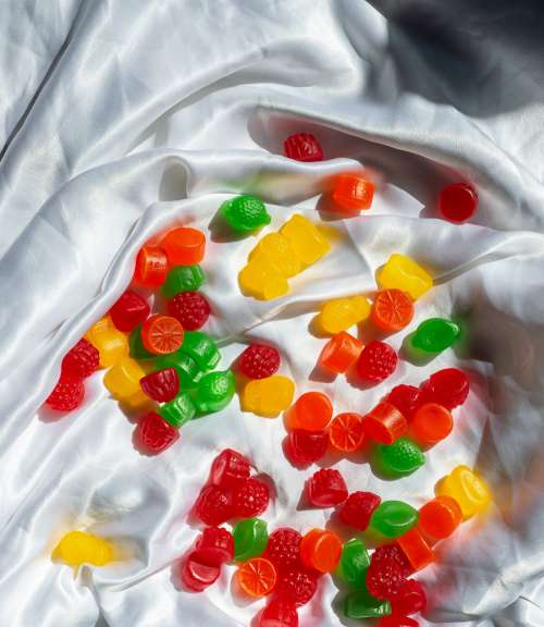 Colorful Jube Jubes Lay In The Folds Of A White Silk Sheet Photo