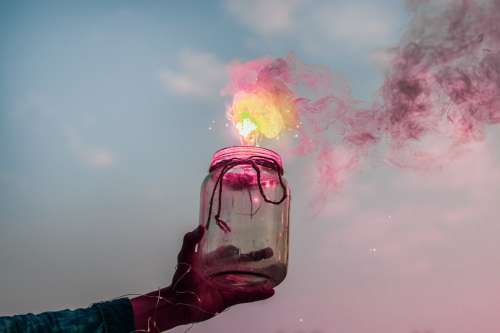 Hand Holds A Jar Out That Is Releasing Yellow And Pink Smoke Photo